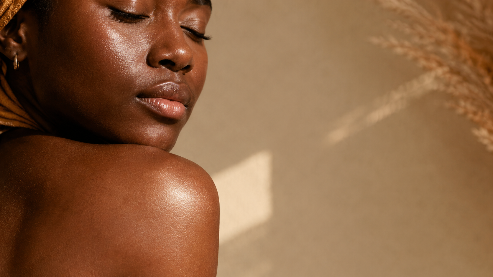 Even-toned, luminous deep skin shoulder and jaw in warm light