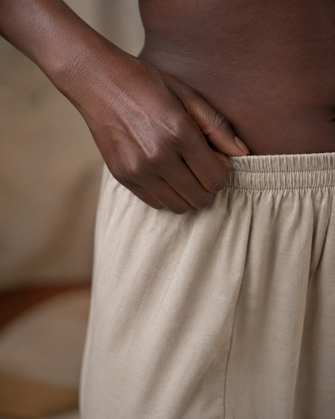 Deep brown skin showing subtle friction darkening at a fold, in warm light.
